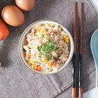 Boiled white rice in ceramic pot on wooden background.