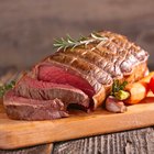 Man's hands dipping piece of roasted pork to ketchup