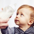 Baby boy drinking milk from a bottle in sunny nursery