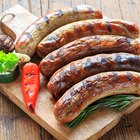 grilled bratwurst sausages with sauce, spinach and garlic