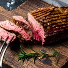 Human hand is preparing BBQ steak for party.