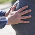 Three women sitting on sofa, two feeling pregnant woman's bump