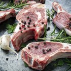 Sliced rare grilled steak on rustic cutting board with set of grilled vegetables on dark rustic wooden table with copy space