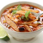 Bowl of tortilla soup with a spoon, served with lime wedge