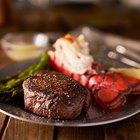 Grilled lobster tails on a plate wit asparagus and lemon wedges