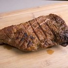 Cuts of warm, pink roast beef on a wooden surface