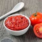 Whole canned tomatoes in brown bowl on wood.