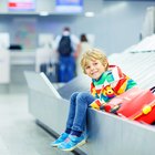 Little boy sitting on a suitcase at the airport