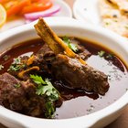 Raw lamb leg on blue stone background with herbs