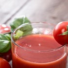 Ripe tomatoes and glass of tomato juice on wooden table