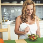 Beautiful pregnant woman holding a bowl of salad while standing