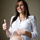 Pregnant woman is standing on the green lawn.