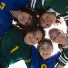 Female (11-13) footballer with trophy, other hand raised, smiling