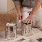 Pregnant woman on floor by paint pots, looking at fabric samples