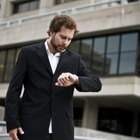 Mid adult man standing at street, looking at watch