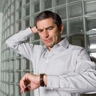 Mid adult man standing at street, looking at watch