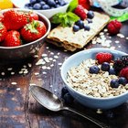 Rolled oats flakes in white porcelain spoon on sackcloth background