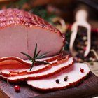 Delicious smoked ham on a wooden board with spices.