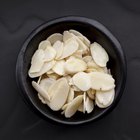 sliced and whole raw almonds on wooden surface