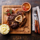 Man's hands dipping piece of roasted pork to ketchup