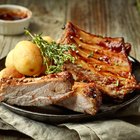 Sliced rare grilled steak on rustic cutting board with set of grilled vegetables on dark rustic wooden table with copy space