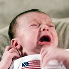 Pregnant woman holding crying girl while talking on telephone