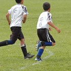 Boy sitting on soccer ball (portrait, low angle view)
