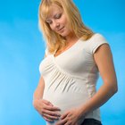 Pregnant woman lying on bed with her hand at belly