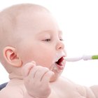 Person spoon feeding baby in high chair