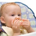 Mother Feeding Baby Sitting In High Chair At Mealtime