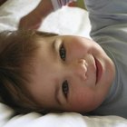 Child playing with blanket on bed