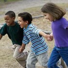 Five children (7-11) running with plastic hoops in park (surface level)