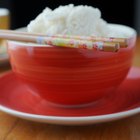 Boiled white rice in ceramic pot on wooden background.