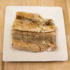 Fish and spices on a wooden cutting board.