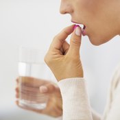 Woman taking a vitamin supplement with a glass of water.