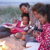 A family by the fire camping out on the beach.
