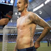David Beckham answers interviews after a game, showing off washboard abs and tattoos.