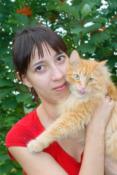 young woman with a red cat image by amlet from Fotolia.com Cat fleas will bite humans.