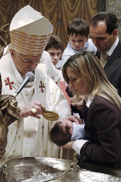 Pope Benedict XVI pours holy water over a baby during a baptism ceremony.
