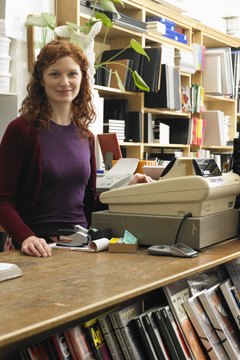 Female shop assistant by cash register in art shop, smiling, portrait