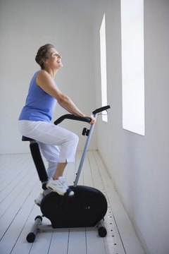 Jupiterimages/Pixland/Getty Images Regular exercise on a stationary bike helps reduce blood pressure.