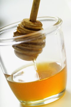 Honey dipper in jar of honey, close-up, tilt