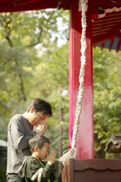 A father and son pray at a Shinto shrine in Japan.