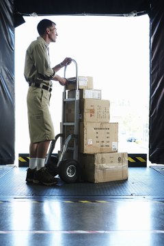 Delivery man standing with boxes in loading bay, side view