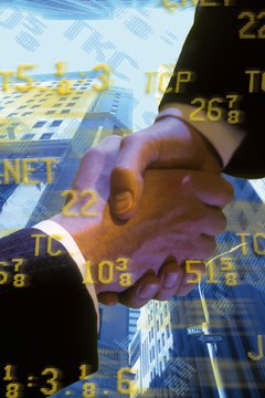 Businessmen shaking hands with stock quotes and buildings