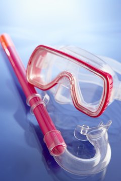 BananaStock/BananaStock/Getty Images Snorkels attach to snorkeling masks to enable you to see and breathe with your face in the water.