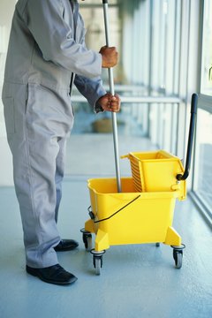 man standing in a corridor with a mop and a bucket