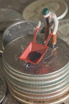 Figurine with miniature wheelbarrow on stack of coins