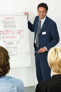 Businessman giving presentation, smiling, colleagues in foreground