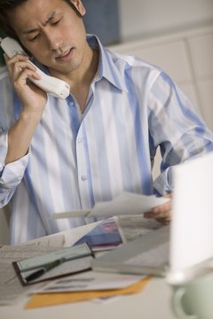 Man talking on phone while doing bills
